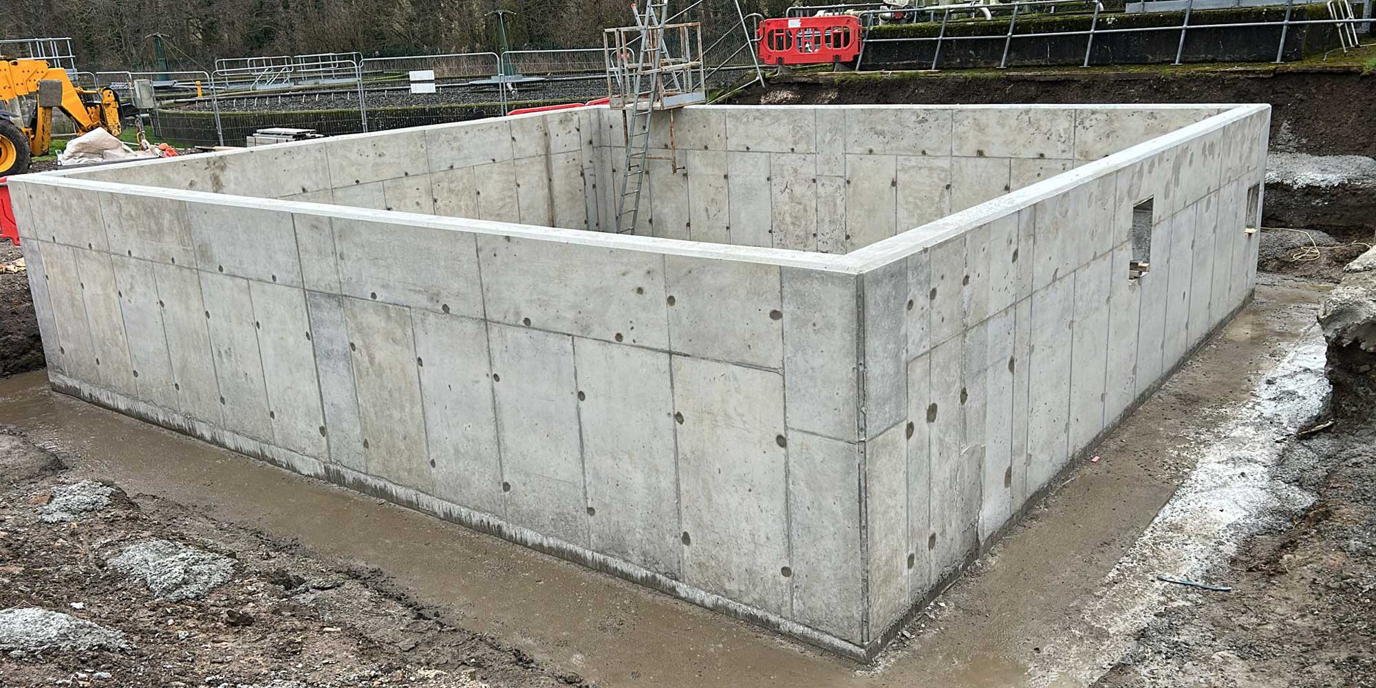 In situ poured rectangular reinforced concrete tank under construction on a Tank Consult project site, with exposed walls, internal access ladder and surrounding groundworks.