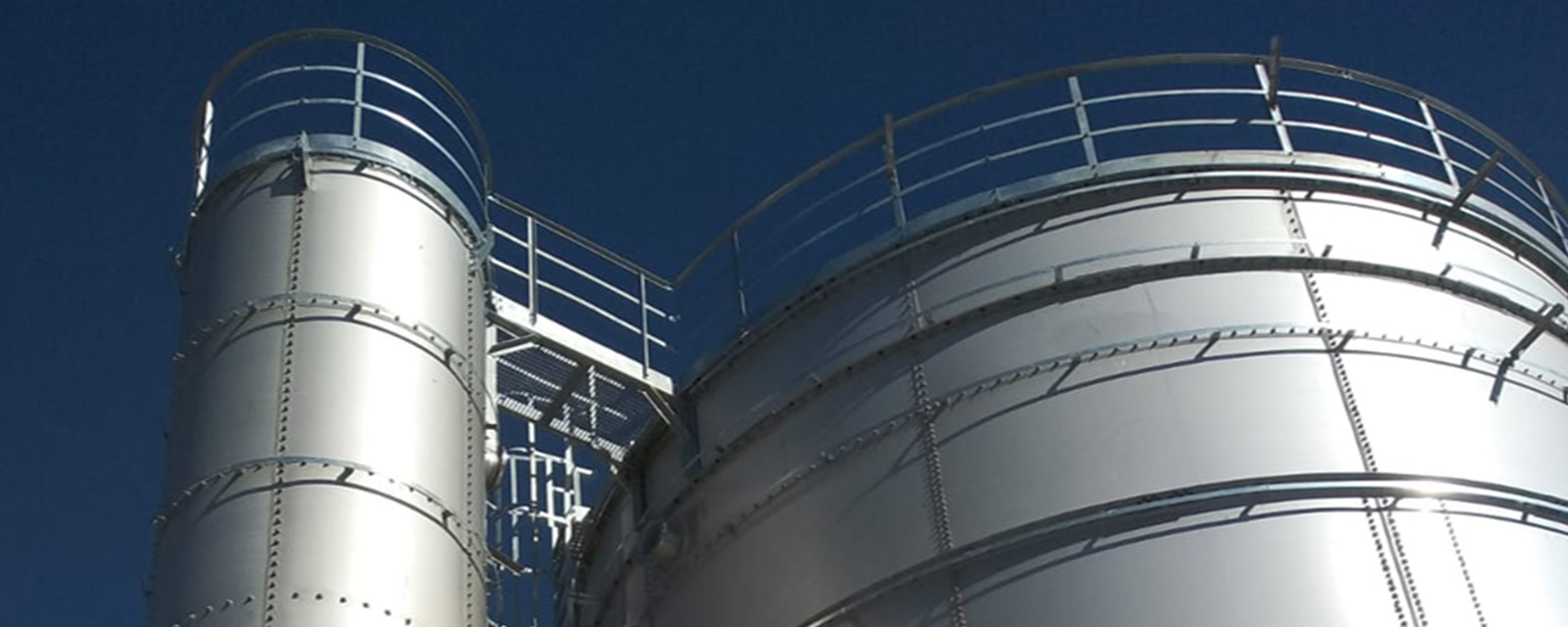 Close‑up upward view of stainless steel tanks with external access platforms and supports